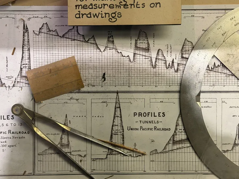 Union Pacific's tunnel profiles under glass: engraved cross-sections of Weber Cañon and its neighbors, a steel protractor arc across the sheet, brass dividers resting where an engineer would have left them.