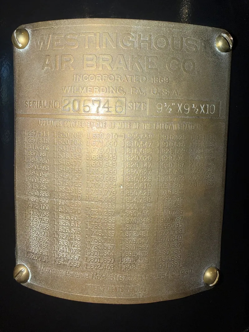 The plate itself: curved brass held by four slotted screws, "Westinghouse Air Brake Co., Incorporated 1869, Wilmerding, PA," serial and cylinder sizes stamped in their boxes, and below, six tight columns of patent numbers — sixteen years of inventions cast into one rectangle.