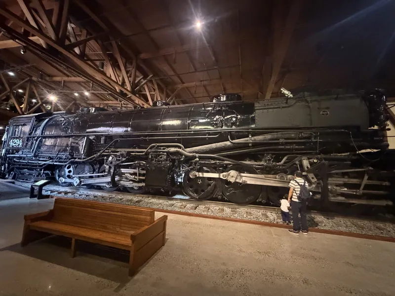 The full broadside from across the gallery, a wooden bench and a father and child at her wheels for scale. All 650,000-plus pounds of her at rest.